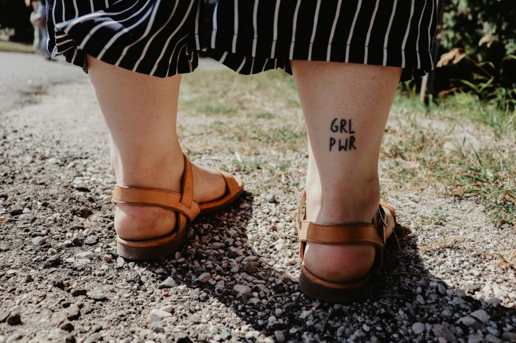 Small symbol tattoos on both ankles above leather sandals