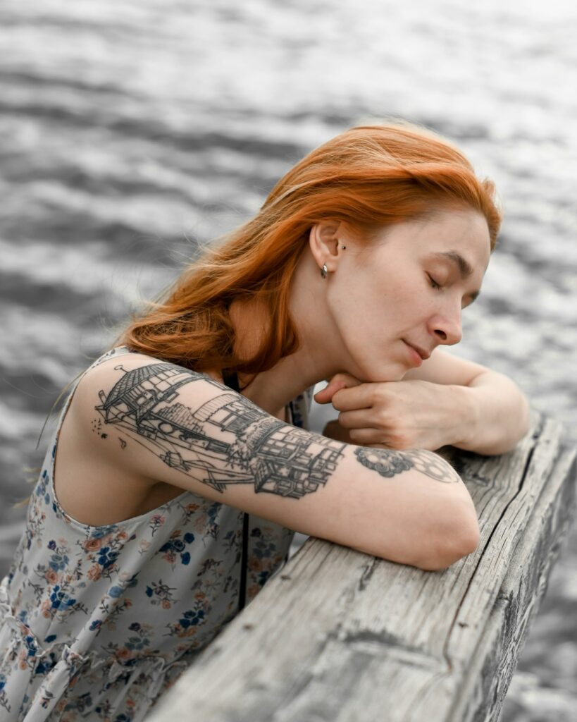 Woman lying on the beach with a half sleeve tattoo