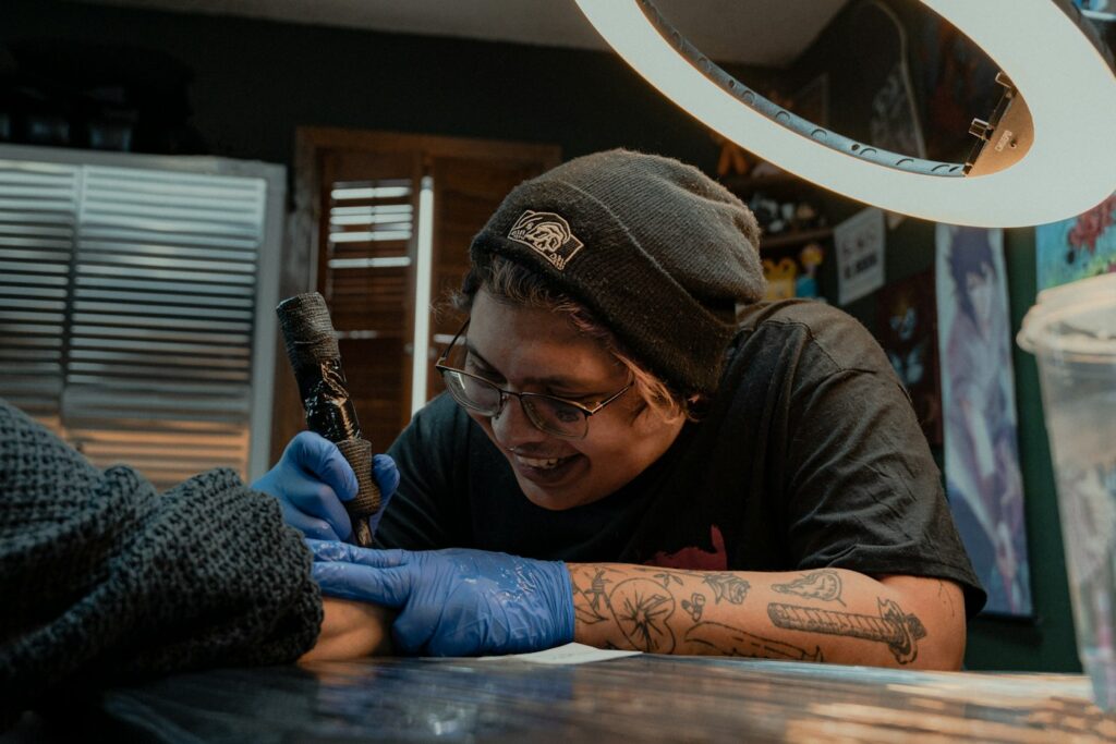 Smiling tattoo artist working on a client