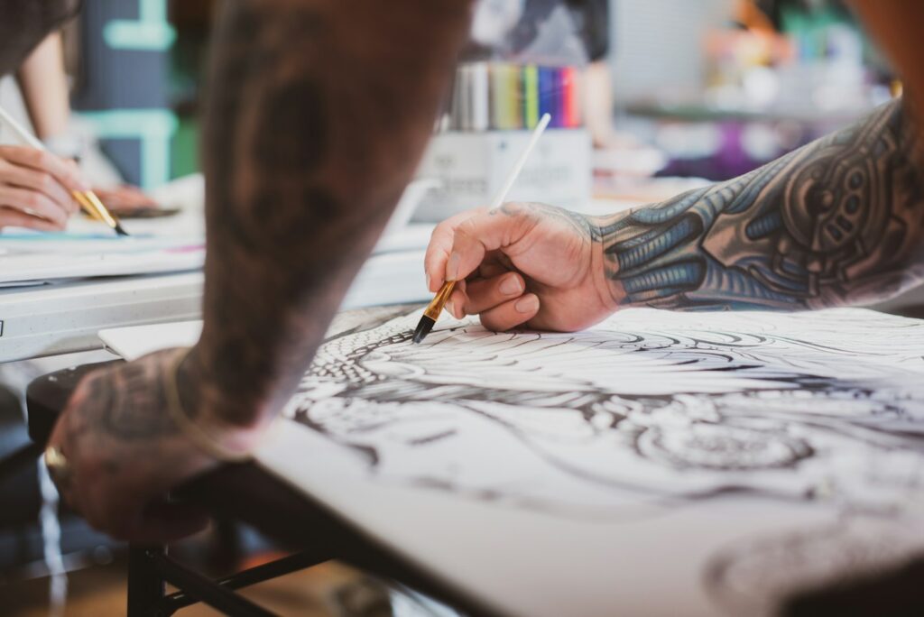 Tattooed artist painting a tattoo flash design