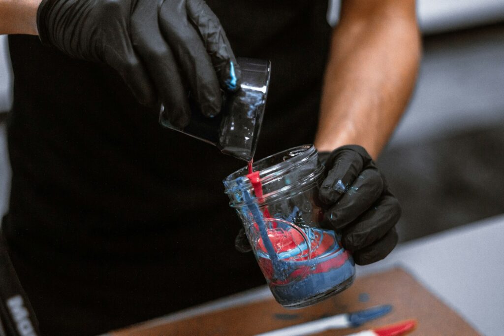 Gloved tattoo artist preparing a rinse cup with colored water