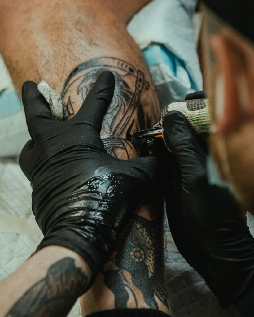 Tattoo artist wiping a fresh leg tattoo
