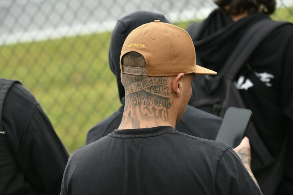 Back of the neck lettering tattoo on a man in a cap