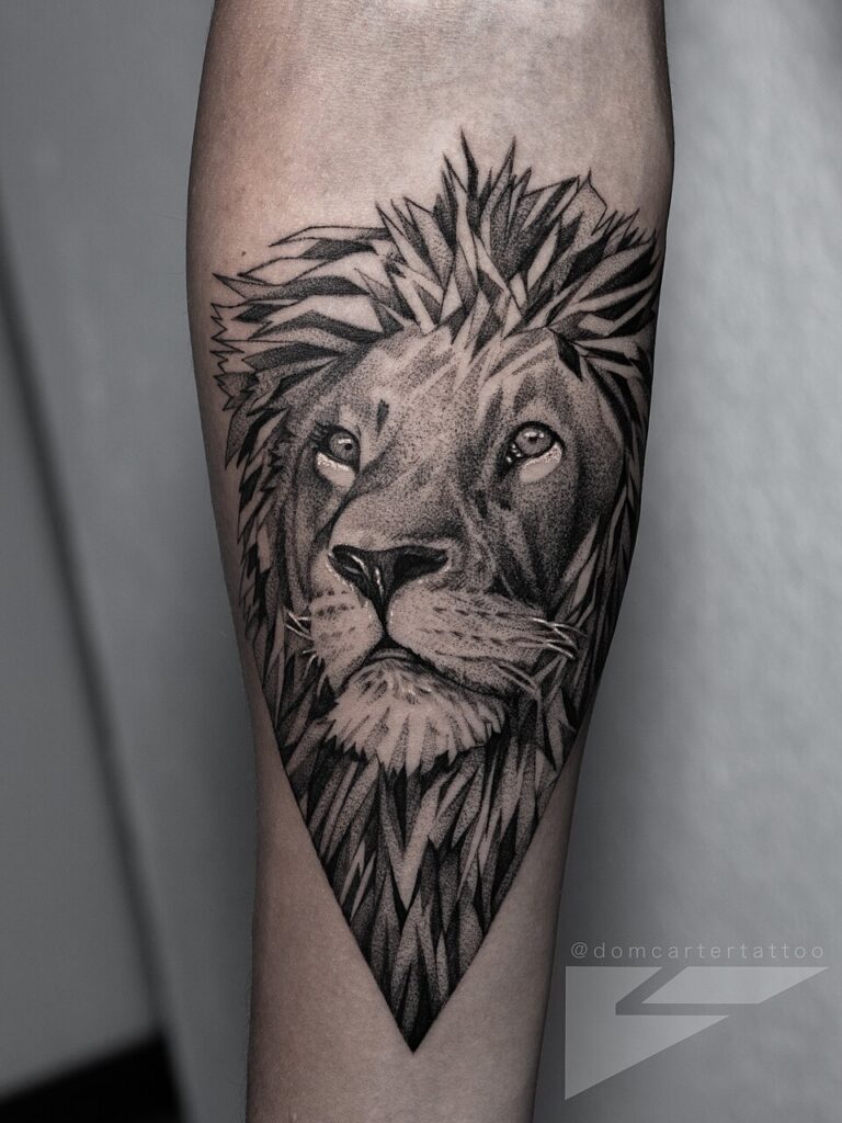 Black and grey lion head tattoo on the forearm