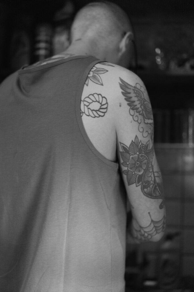 Black and grey shoulder and arm tattoo in a tank top