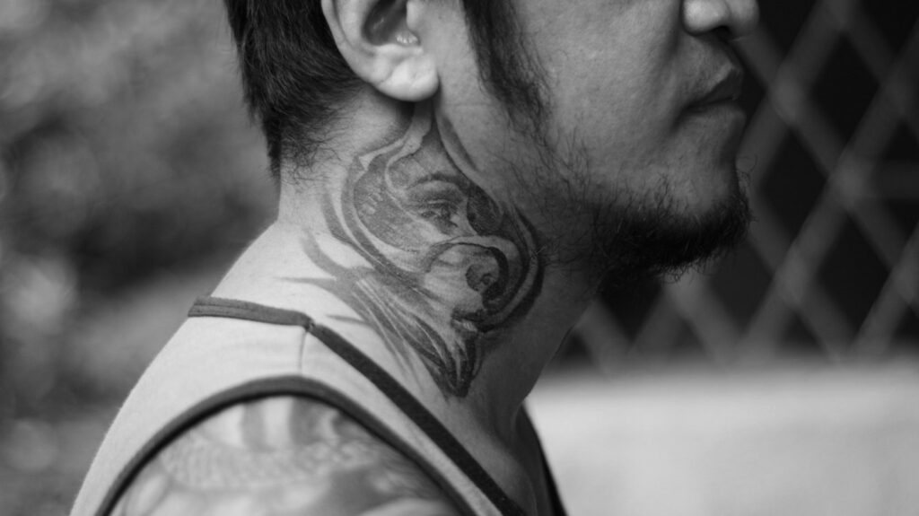 Black and grey realism tattoo on the side of a man's neck
