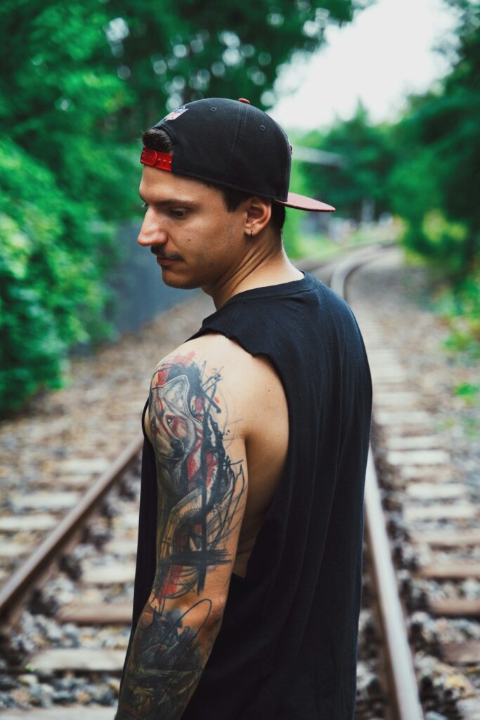 Black sleeve tattoo on a man standing on railway tracks