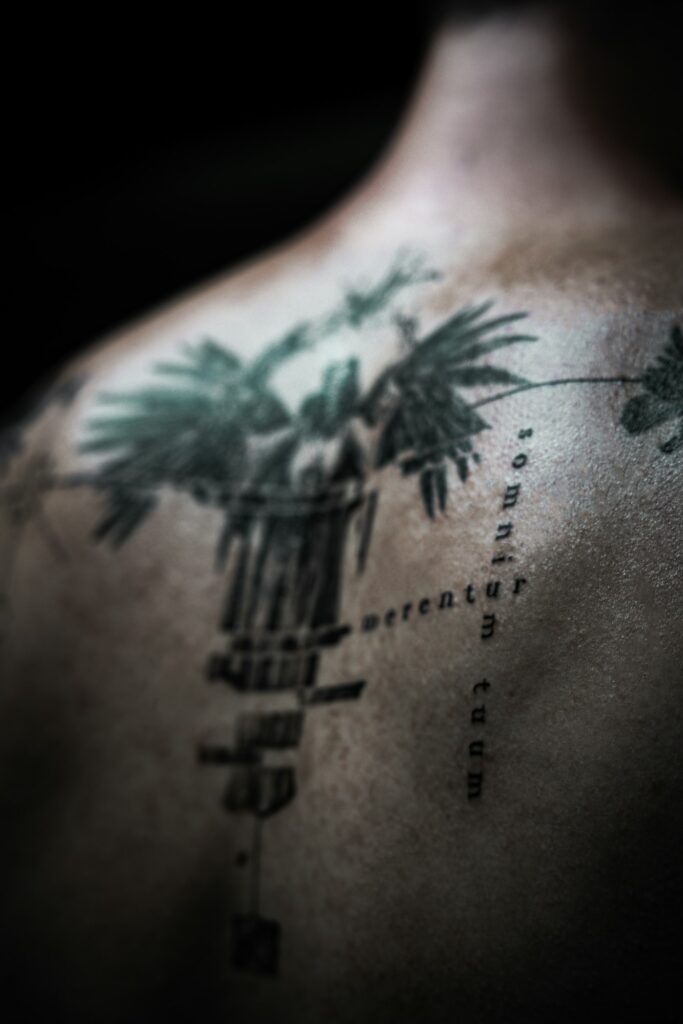 Blackwork and linework back tattoo with a palm tree and dotted lines