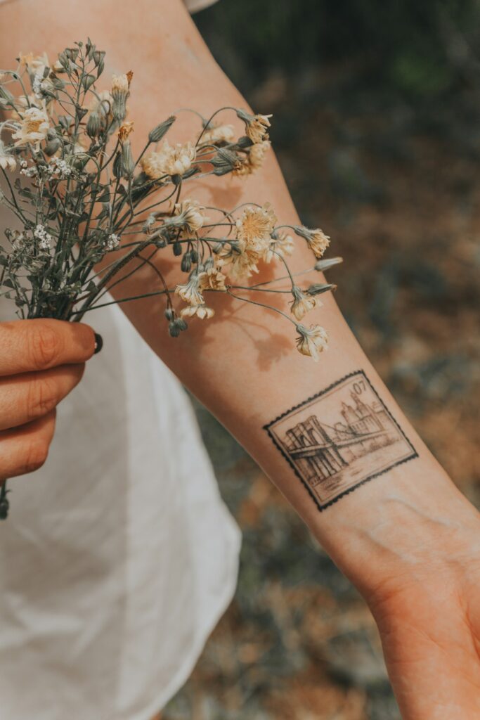 Botanical line tattoo with flowers on the forearm