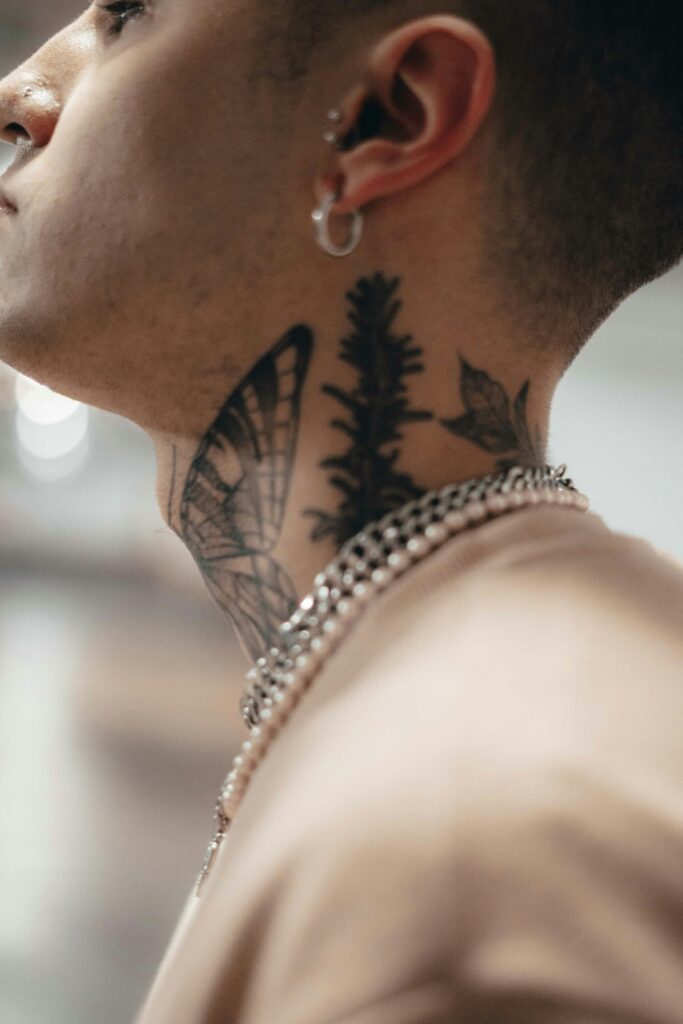 Butterfly and pine side neck tattoo on a man