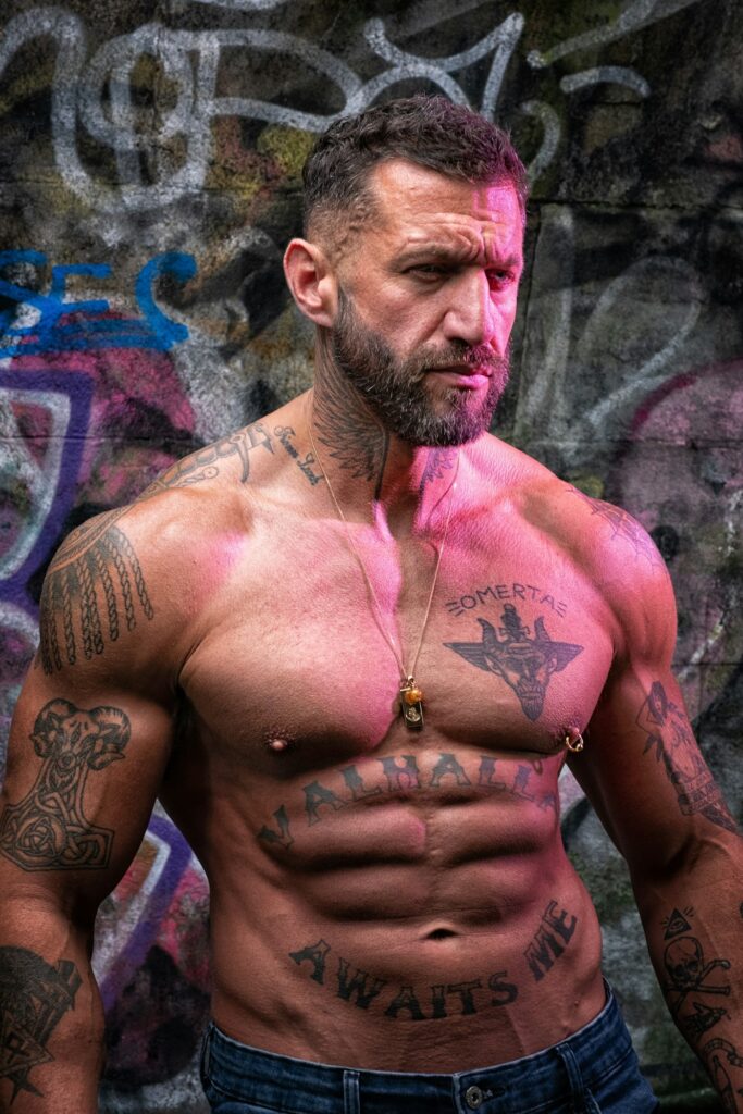 Chest tattoos on a muscular man in front of graffiti
