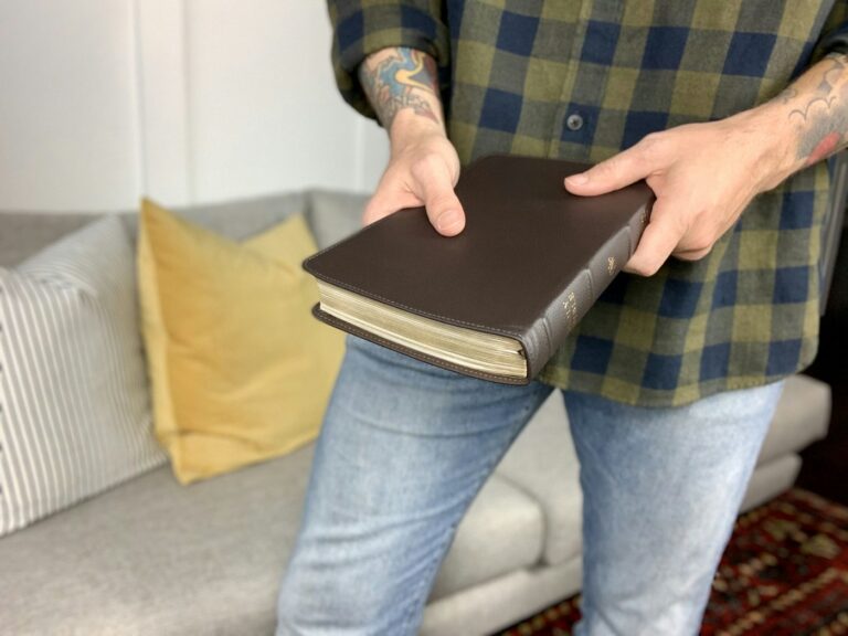 Christian tattoos for men: tattooed man holding a Bible