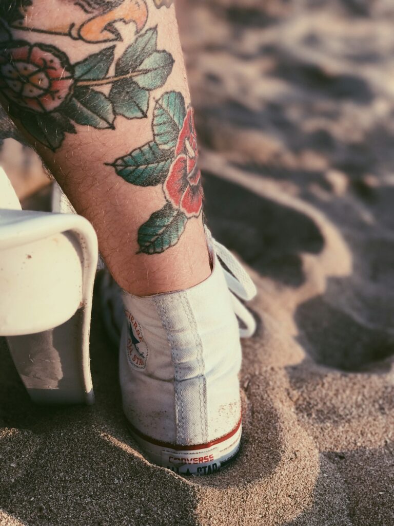 Color floral tattoo on the lower leg above a sneaker