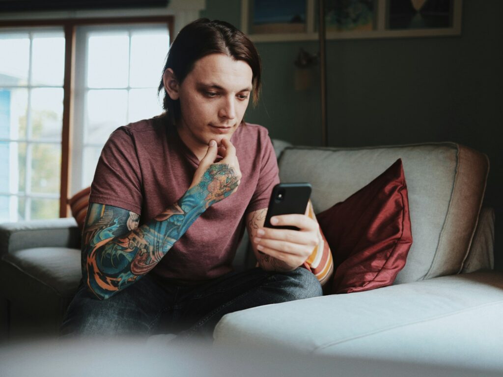 Color sleeve tattoo on a man checking his phone