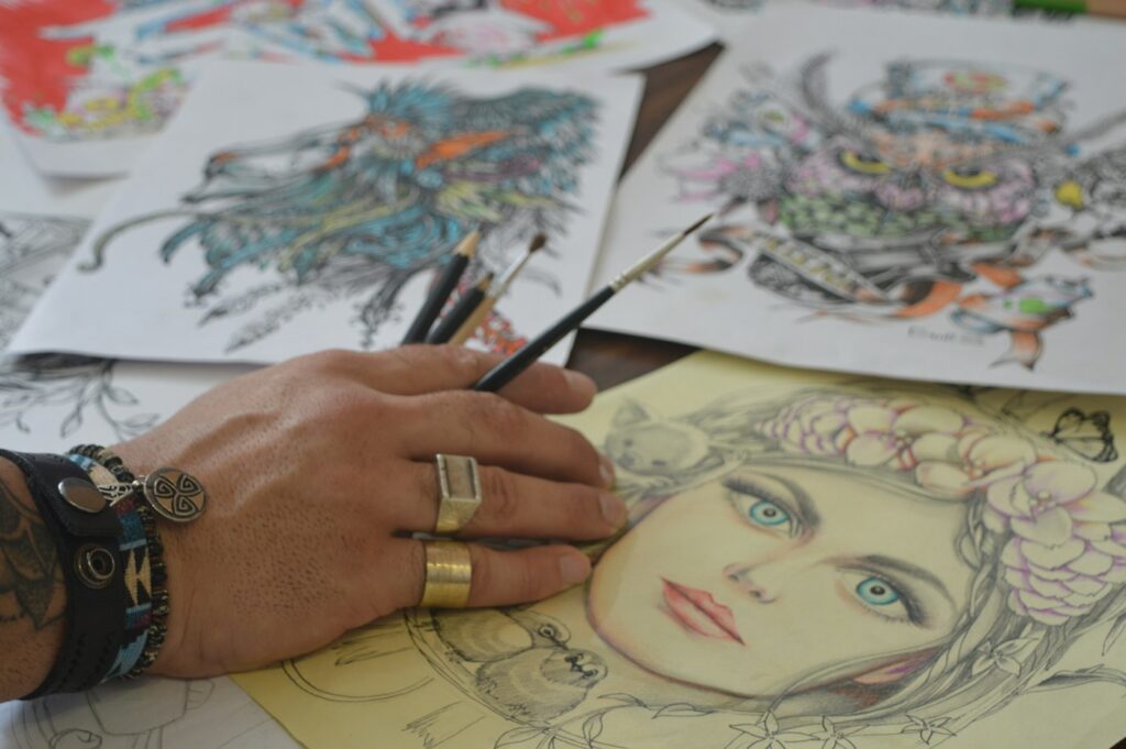 Colored pencil tattoo design drawings spread on a table