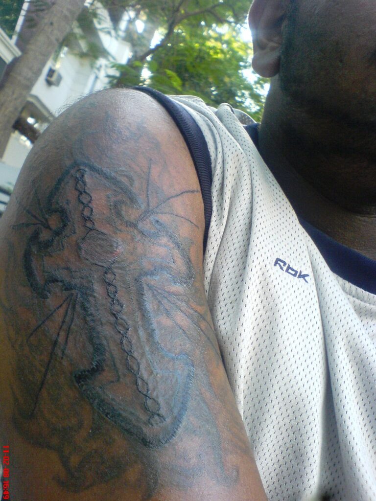 Simple cross tattoo on a man's arm