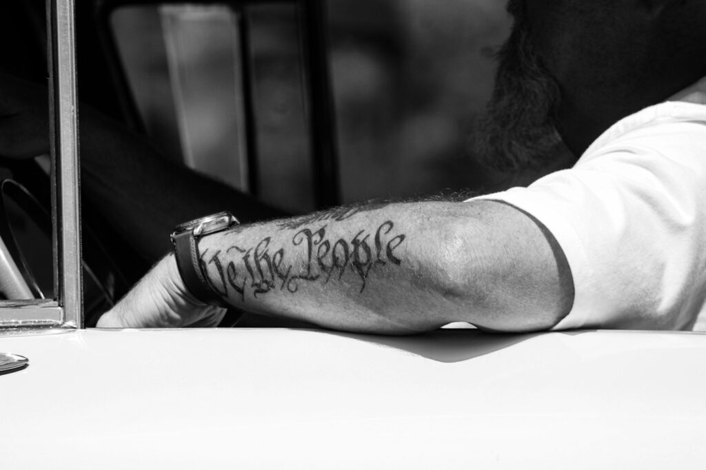Cursive quote tattoo on the forearm in black and white