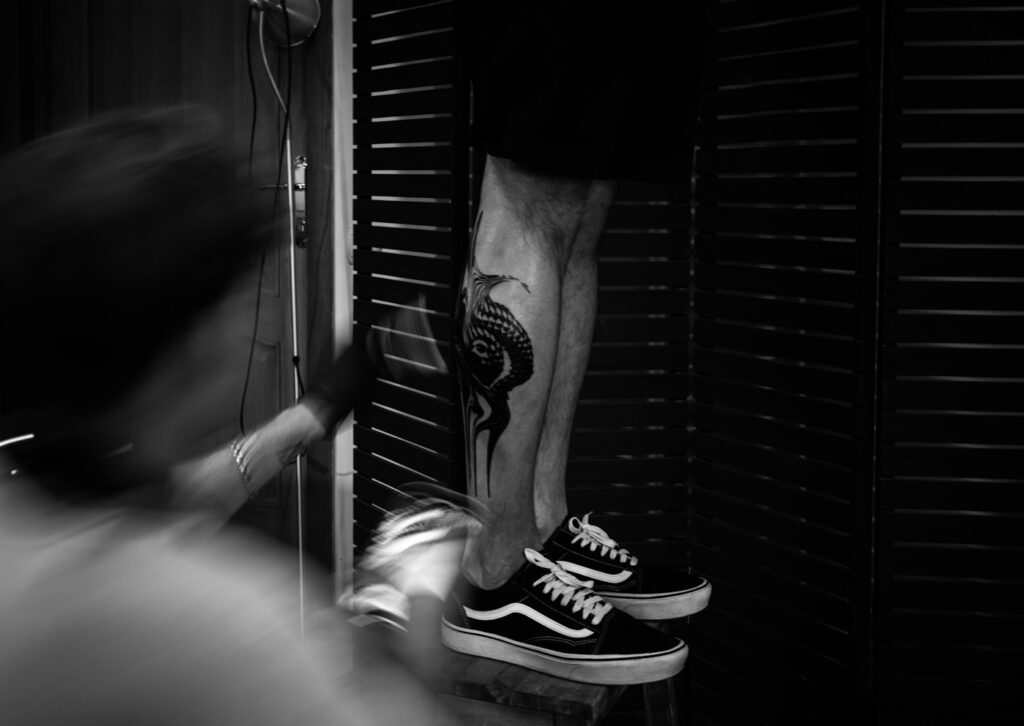 Dark calf tattoo on a man standing in sneakers