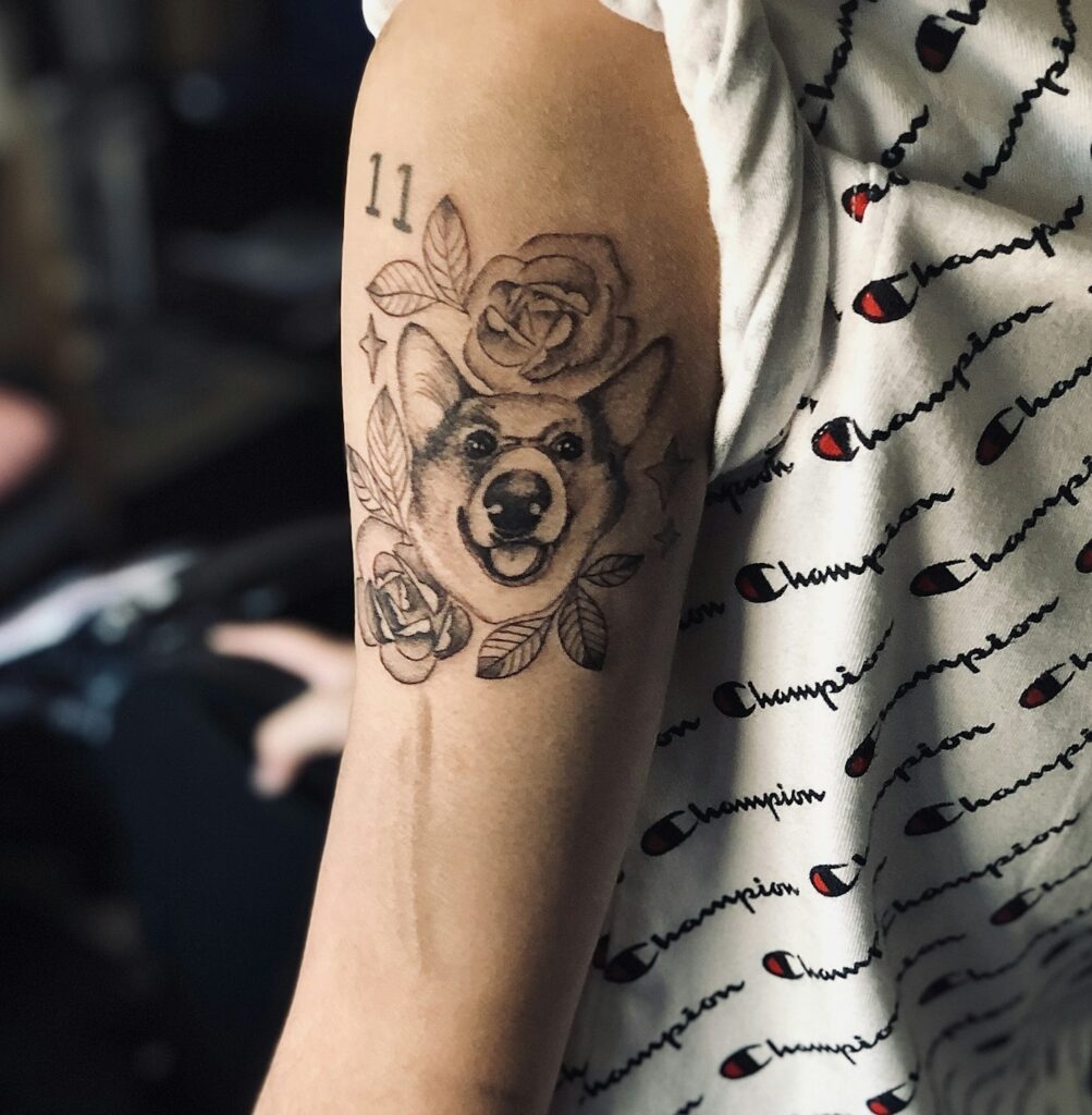 Fine line illustrative tattoo of a dog with roses on the arm