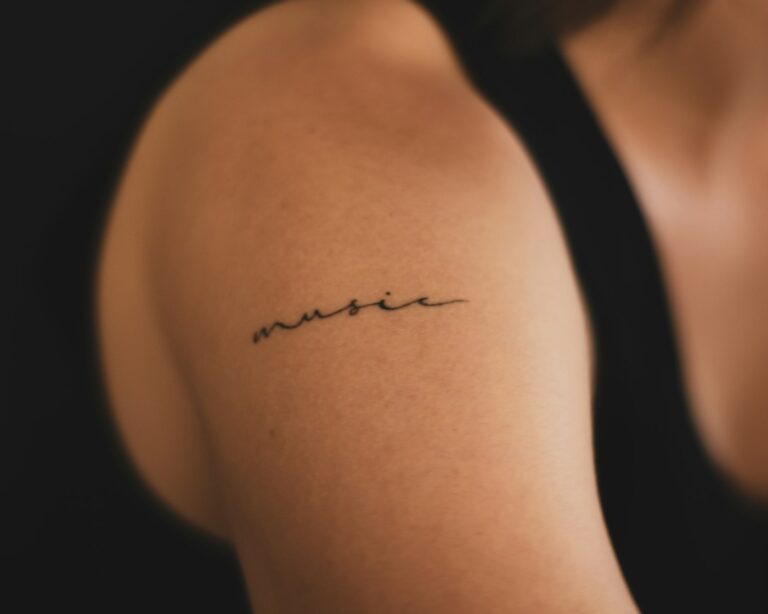 Fine line tattoos: delicate music tattoo on the upper arm