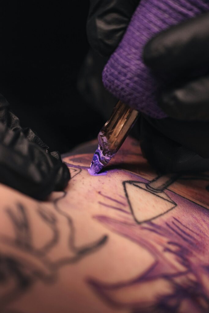 Tattoo artist pulling fine black linework with a rotary machine