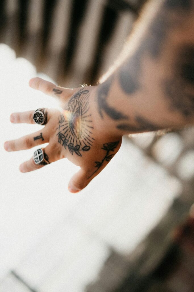 Small symbol finger tattoos worn with silver rings on a man's hand