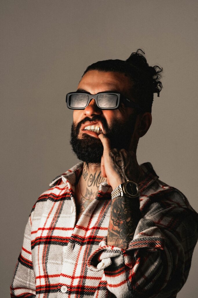 Bearded man in glasses showing tattooed fingers and hand