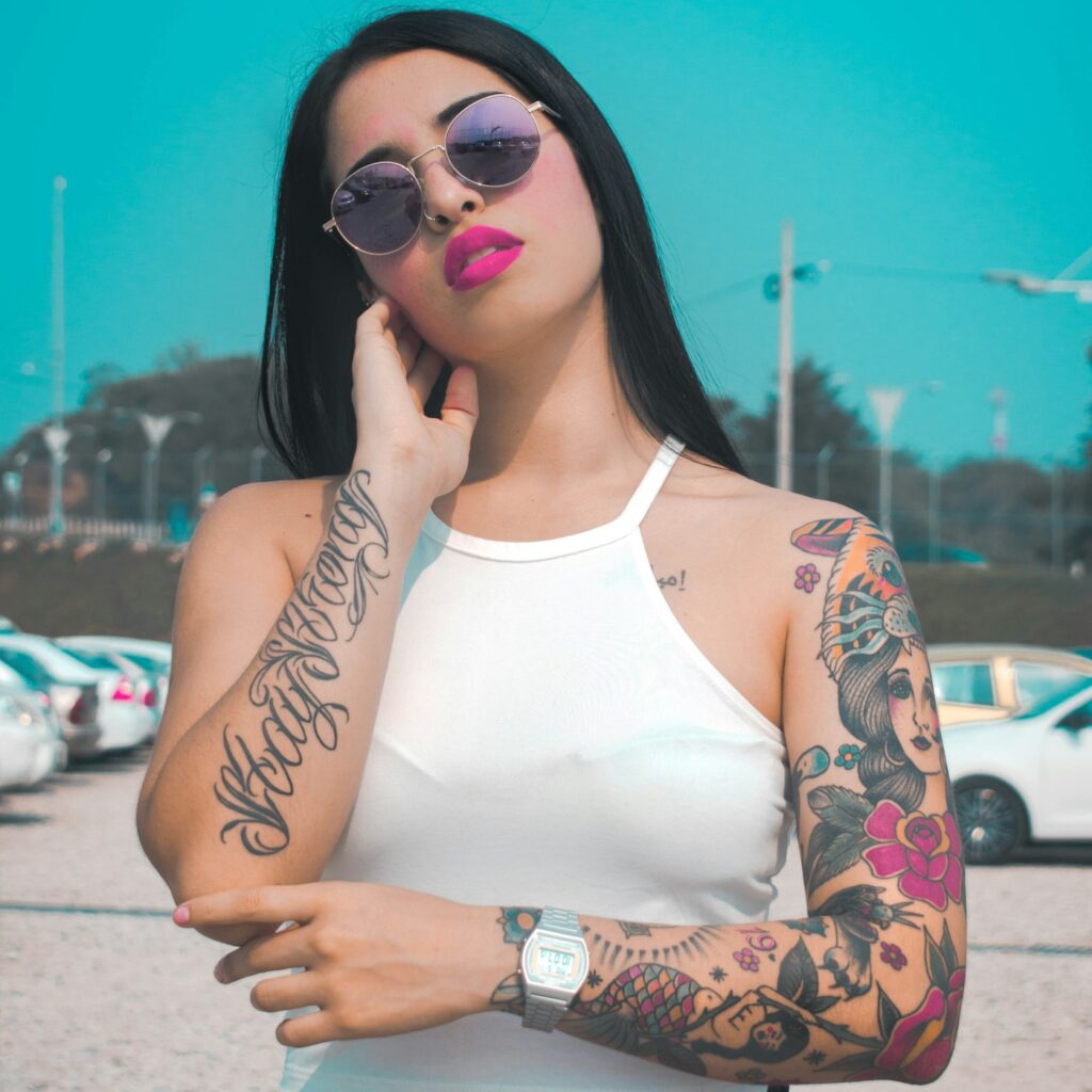Floral tattoos on both arms of a woman in a white top
