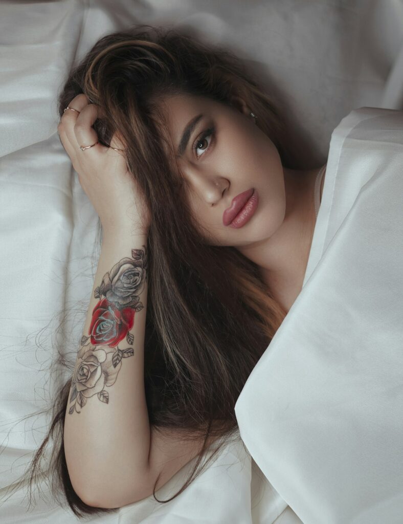 Woman lying in bed with a floral forearm tattoo