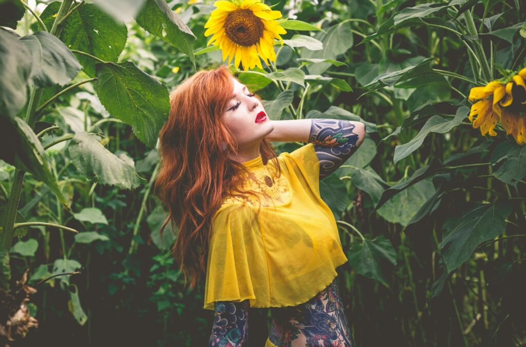 Flower tattoos for women: woman with arm tattoos in a sunflower field