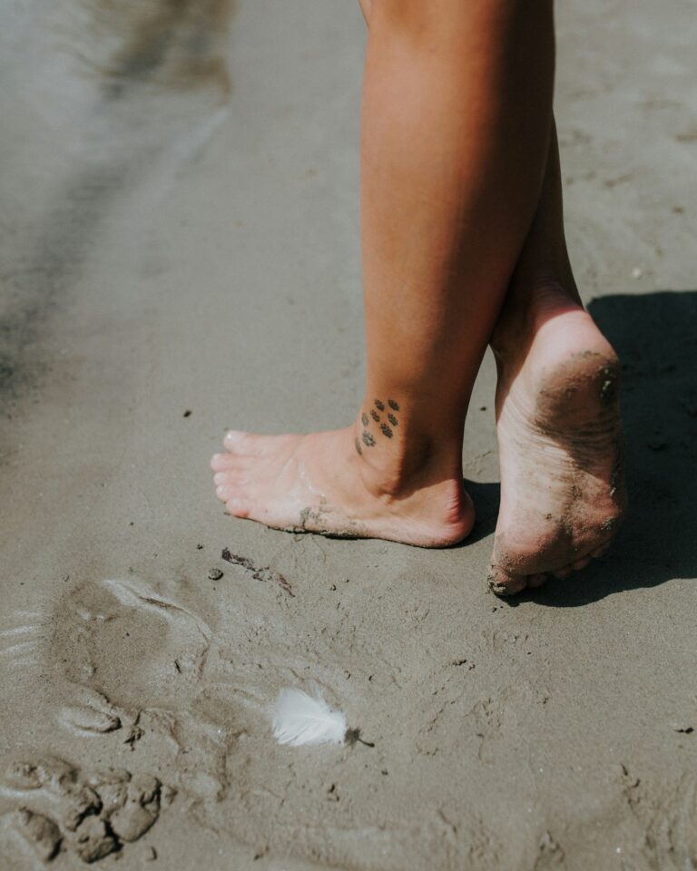 Foot tattoos for women: woman standing barefoot on the beach