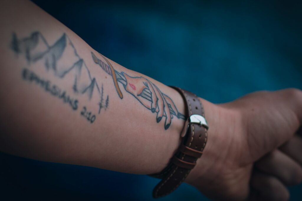 Forearm and wrist tattoo next to a leather watch