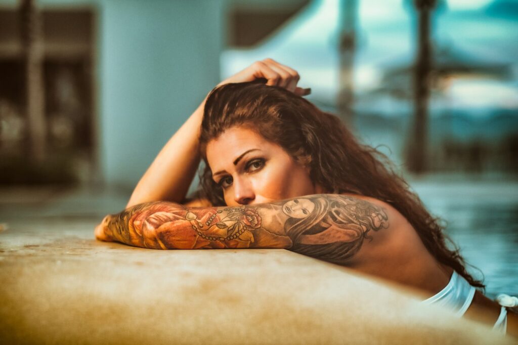 Woman lying down with a full arm sleeve tattoo