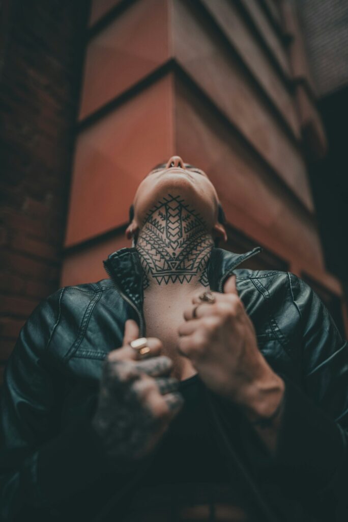 Neck tattoos for men: full throat tattoo on a man tilting his head back