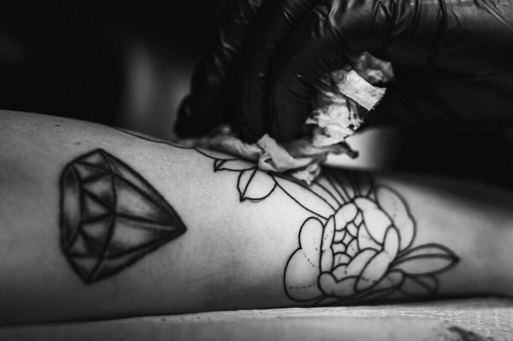 Geometric diamond and rose tattoo on the forearm