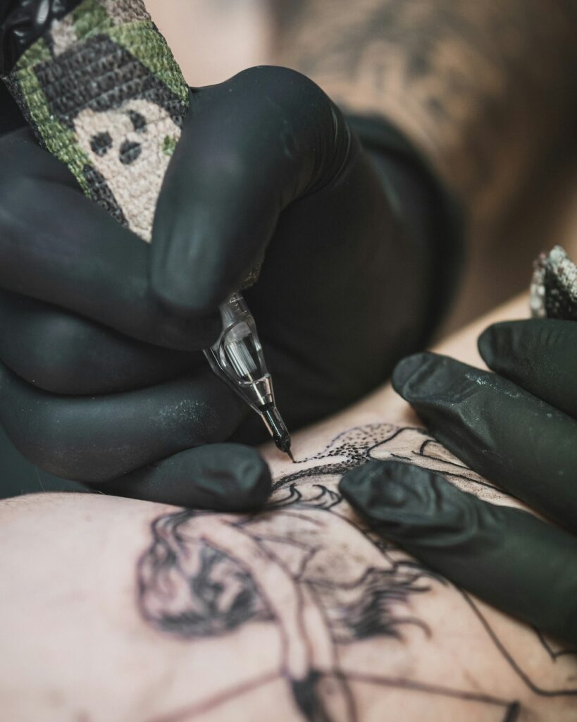 Tattoo artist in gloves tattooing a client