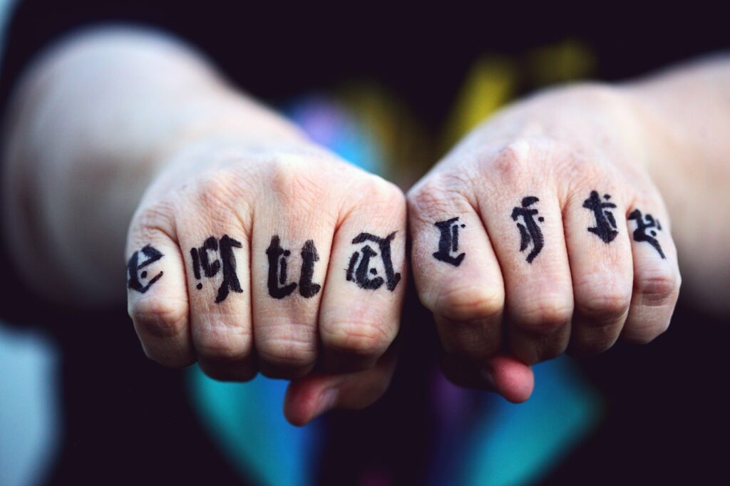 Gothic letter tattoos across the knuckles