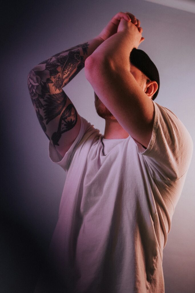 Half sleeve tattoo on a man in soft pink light