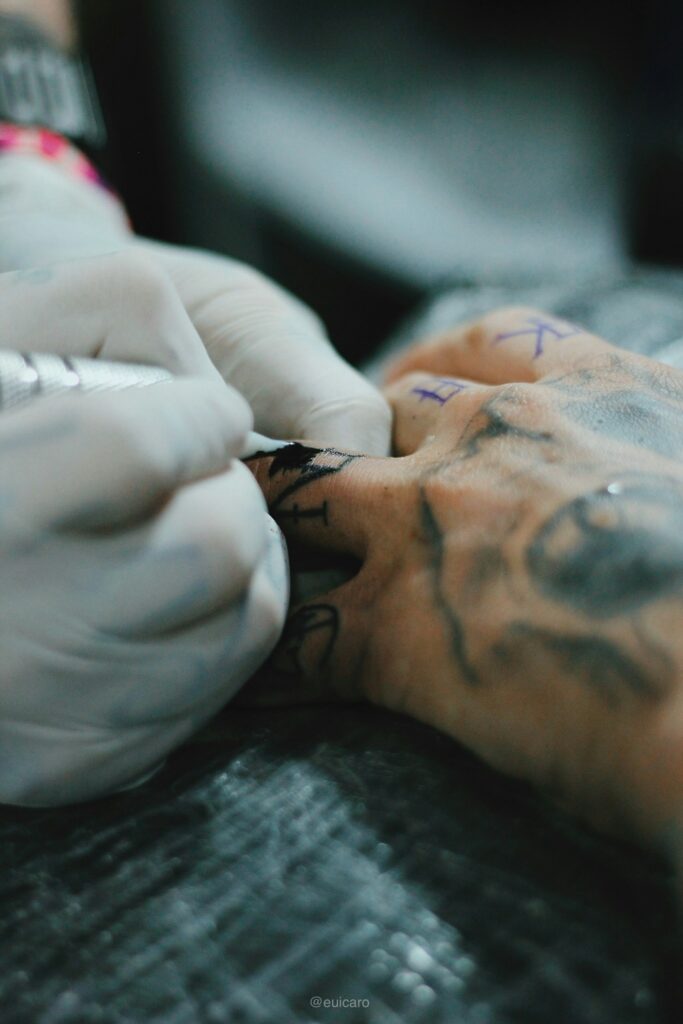 Close up of a gloved artist hand poking a tattoo
