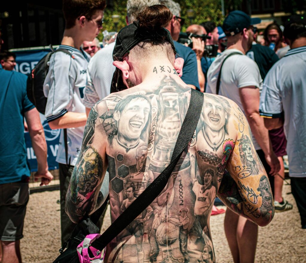 Heavily tattooed back and arms in a crowd