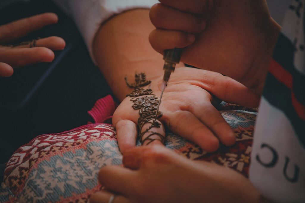 Henna artist applying henna paste with a cone