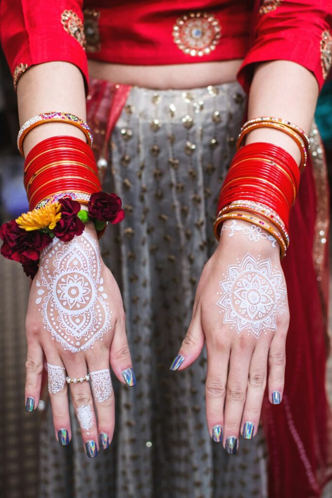 Henna tattoo: bride with white henna designs on her hands and red bangles