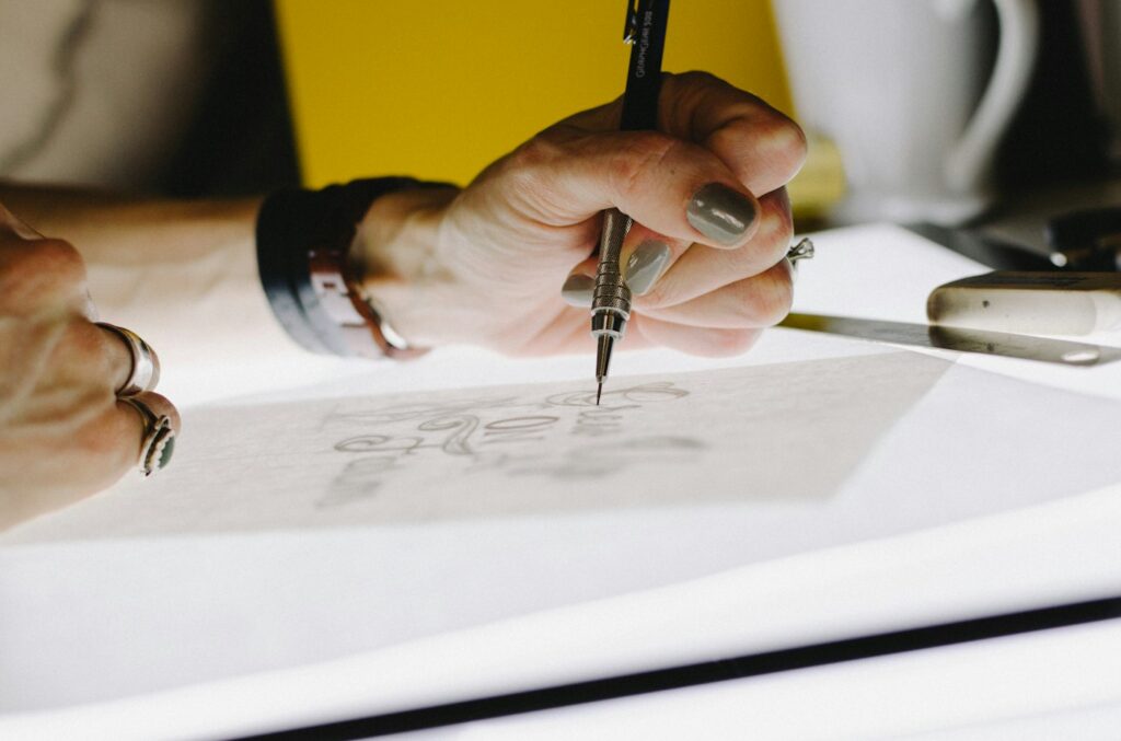 Close up of a hand drawing a design with a fine ink pen
