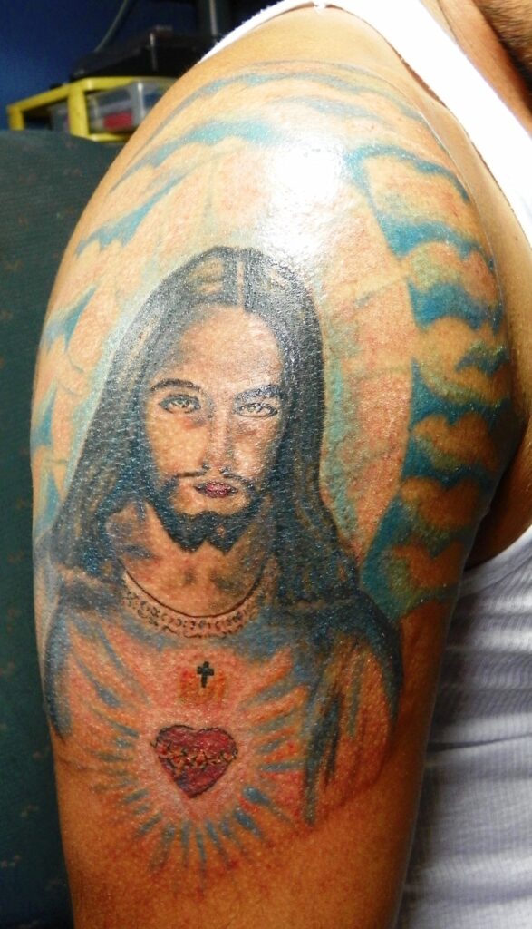 Black and grey Jesus portrait tattoo on the arm