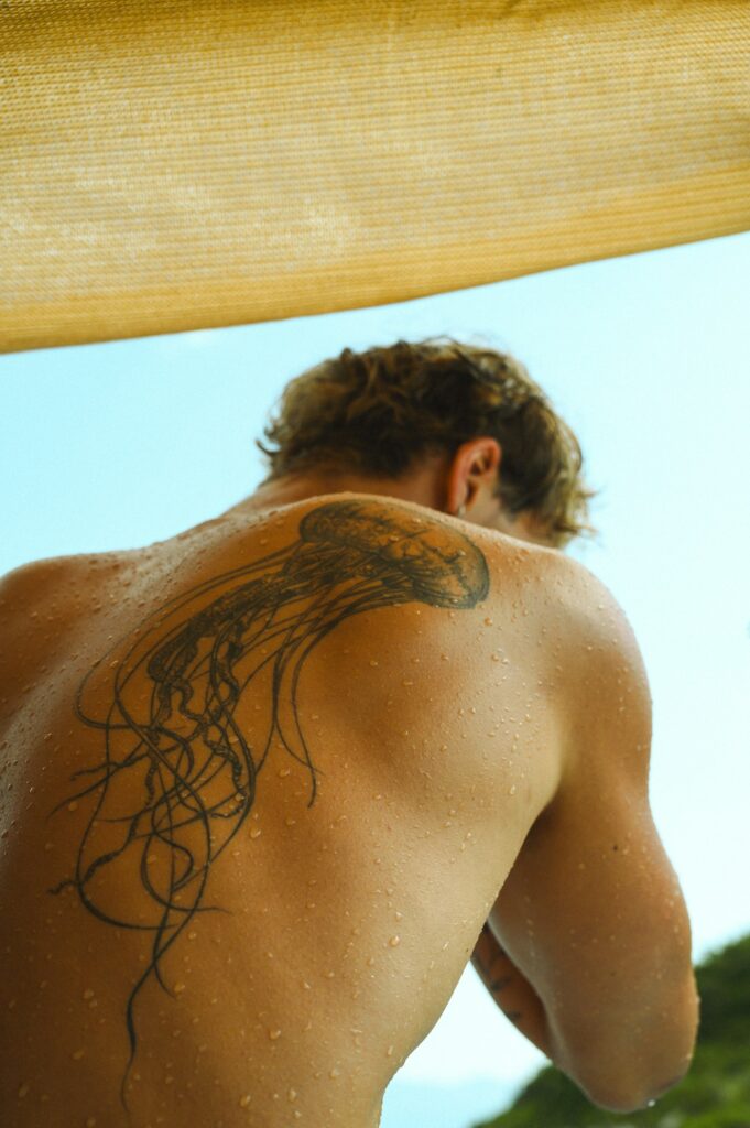 Large tattoo on a man's wet back and shoulder