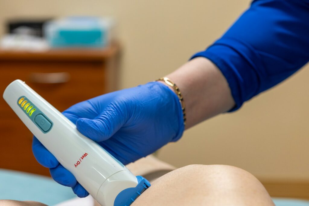 Laser device used on a client's arm by a gloved technician