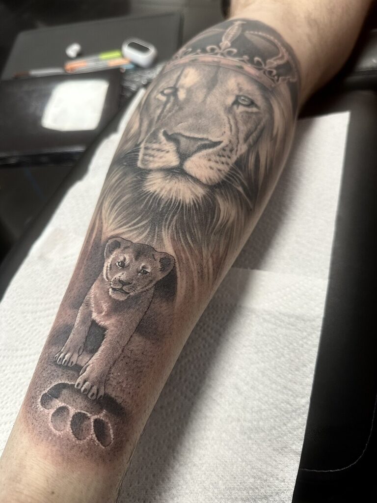 Realistic lion and cub tattoo on the forearm