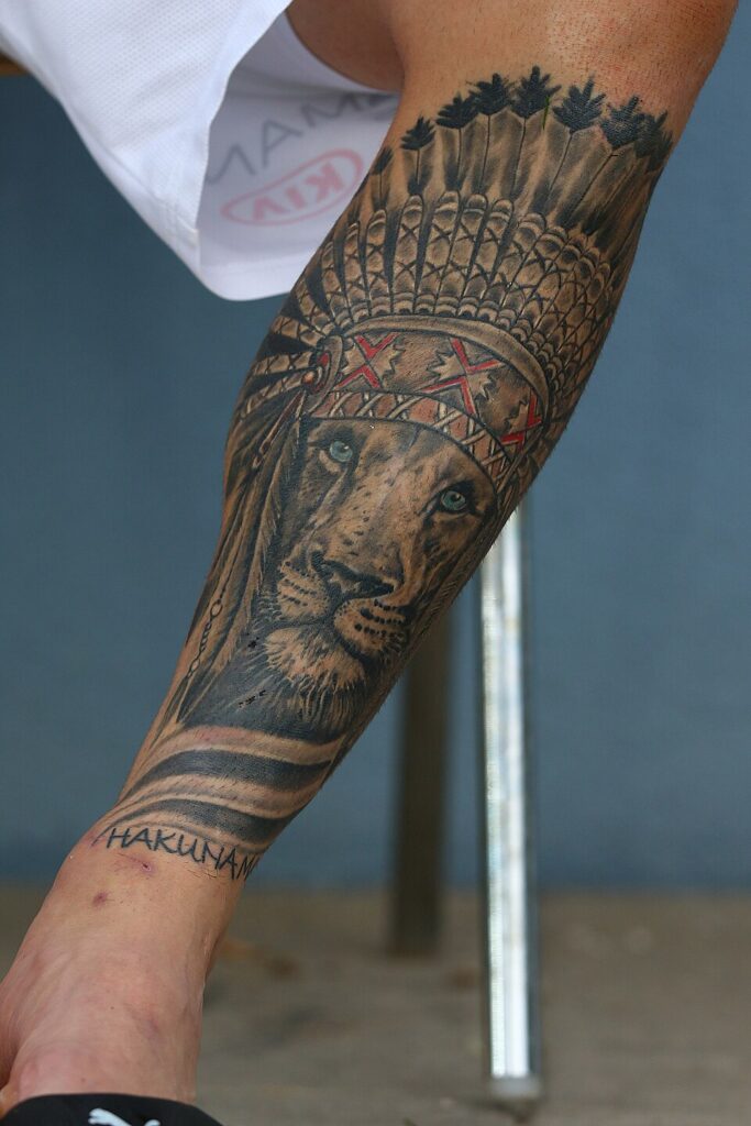 Lion tattoo with a headdress on an athlete's forearm