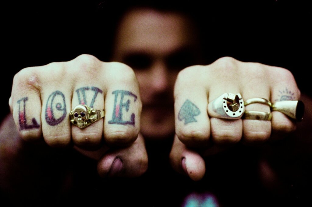 Love lettering and card suit tattoos on the knuckles