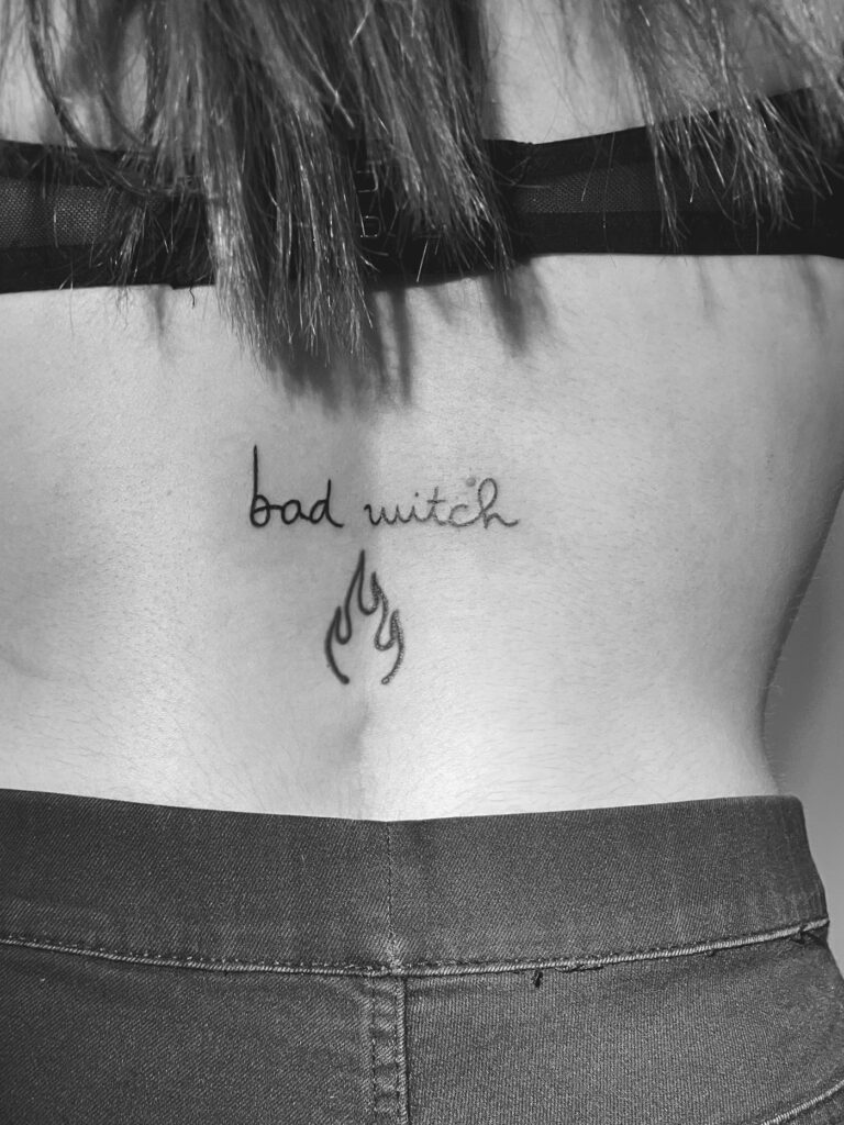 Script and flame tattoo on the lower back